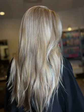 A person with long, straight, ash blonde hair is photographed from behind inside a salon known for offering the best balayage and highlights in Spring Hill TN. | Salon Blonde in Columbia, TN, Spring Hill, TN, Franklin, TN