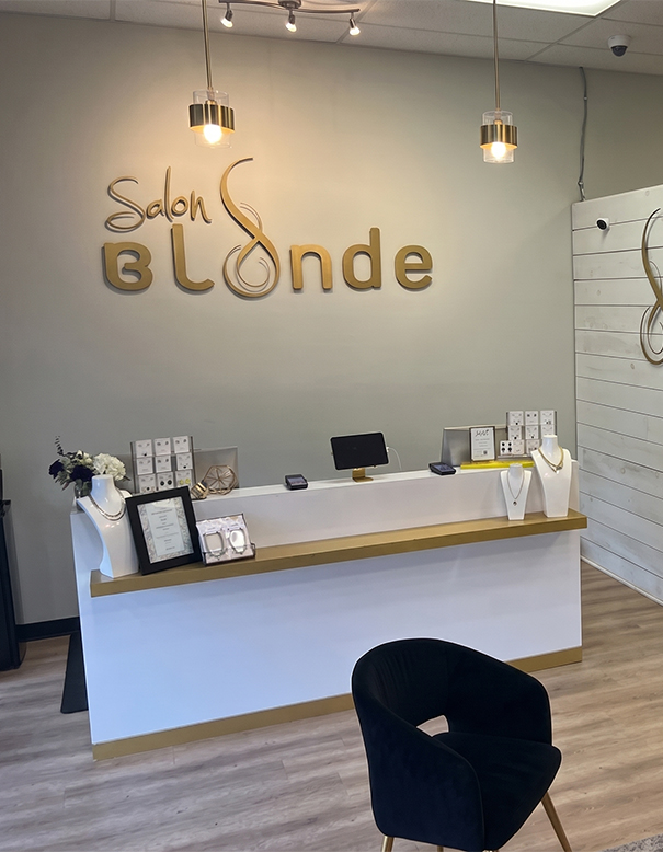 Front desk of Salon Blonde with gold signage on the wall, jewelry display stands, a framed certificate, and a black chair in the foreground—home to the best hair extensions in Franklin TN. | Salon Blonde in Columbia, TN, Spring Hill, TN, Franklin, TN
